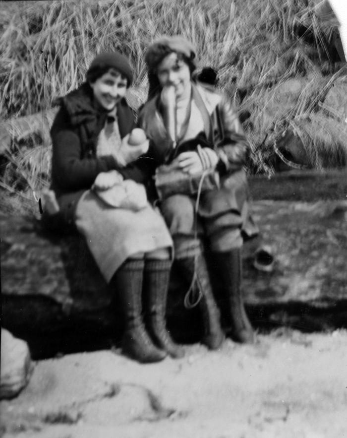 Two women eating lunch on a log