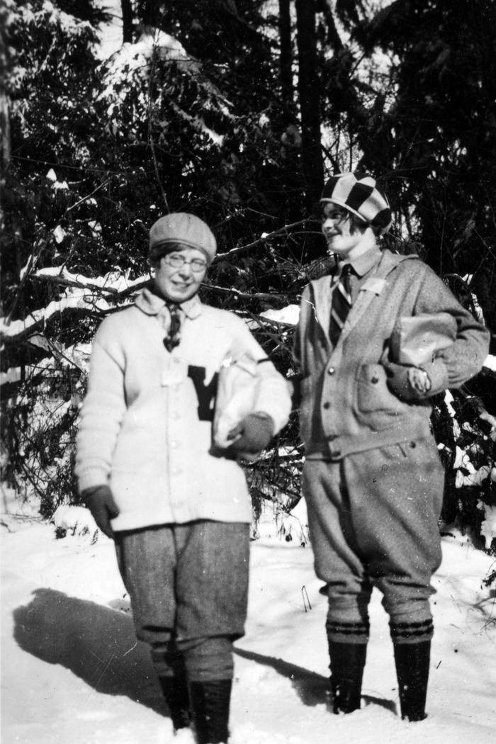 Two women in winter gear and boots standing in snow