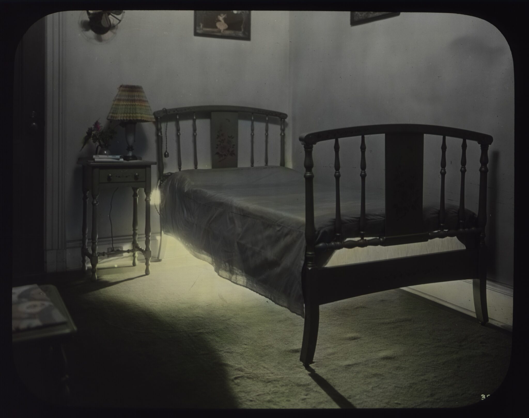 A color photo showing a bed with a light glowing from underneath it.