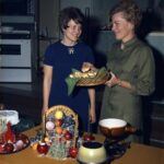 A color photo of two Seattle City Light Home Economists pose with a basket of rolls at a holiday event