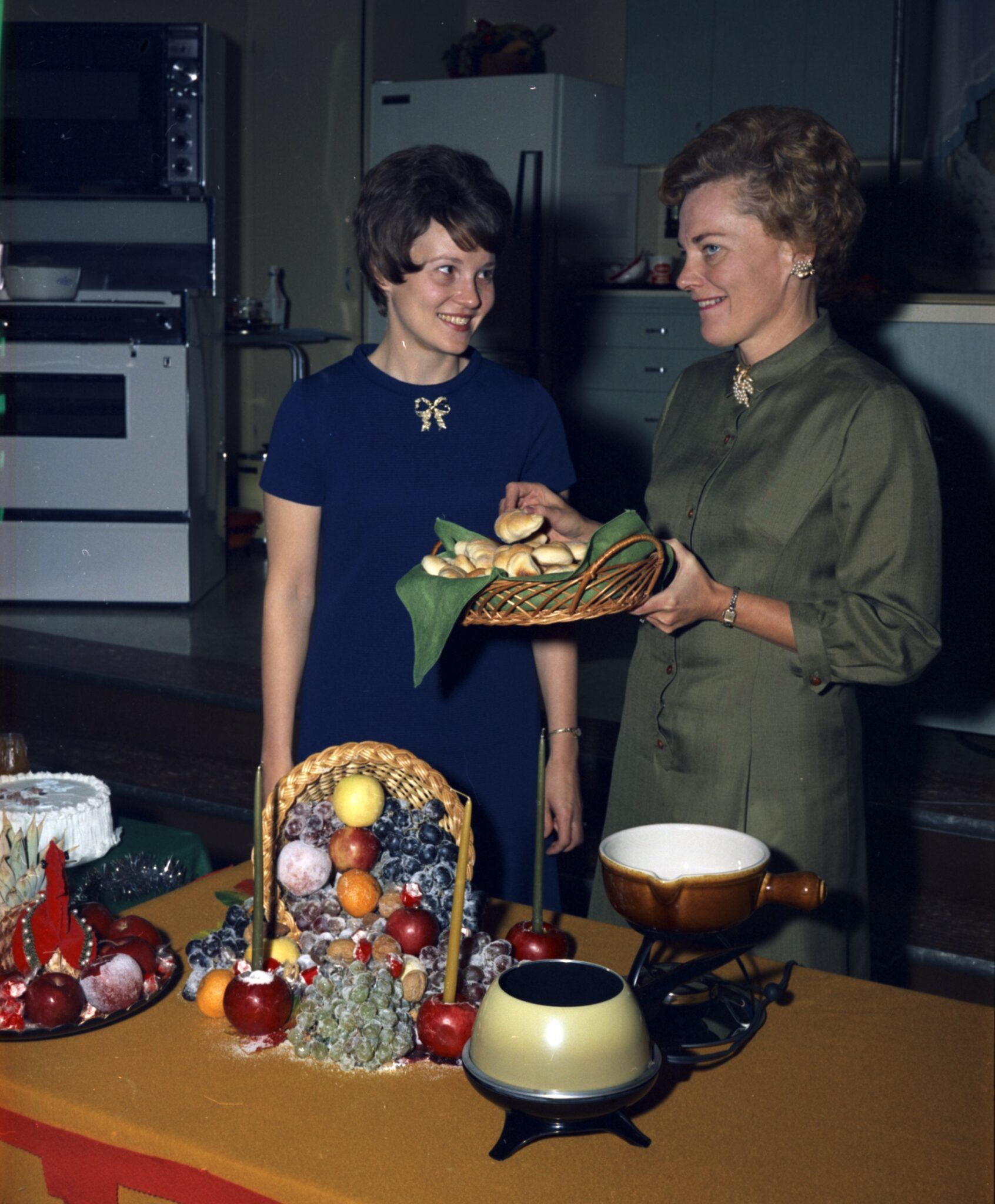 A color photo of two Seattle City Light Home Economists pose with a basket of rolls at a holiday event
