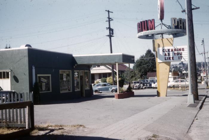 Building with a drive-through canopy and a distinctive mid-century sign out front, apparently situated on an arterial road