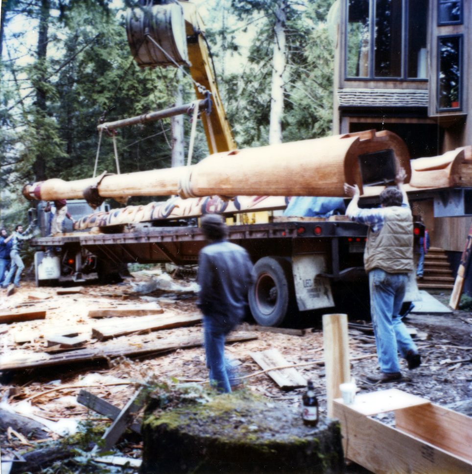 color photo of completed totem poles being loaded onto a flatbed truck