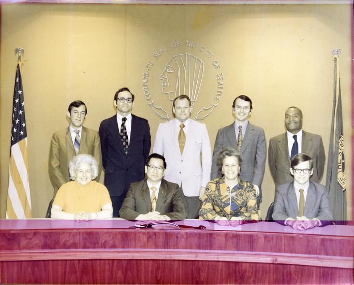 Seattle City Council portrait with all nine members at dais with flags and city seal