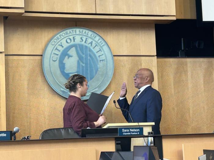 Mark Solomon raising his hand to take the oath of office from City Clerk Scheereen Dedman
