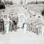 Black and white photo of a group of people at the base of a path leading up a hill