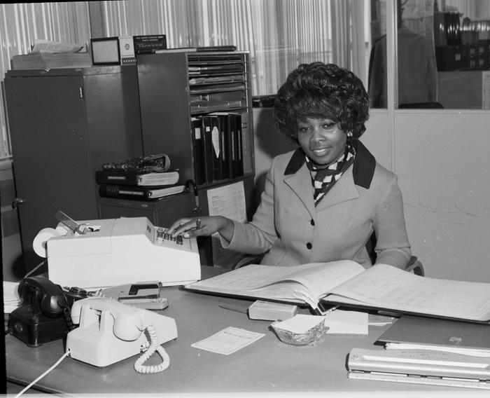 Woman sitting behind a desk using an adding machine