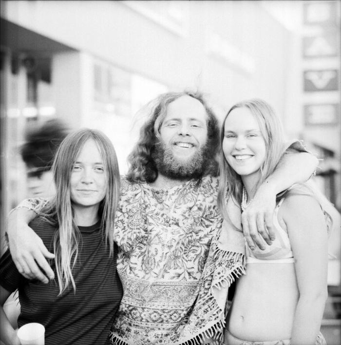 Two women posing on either side of a bearded man