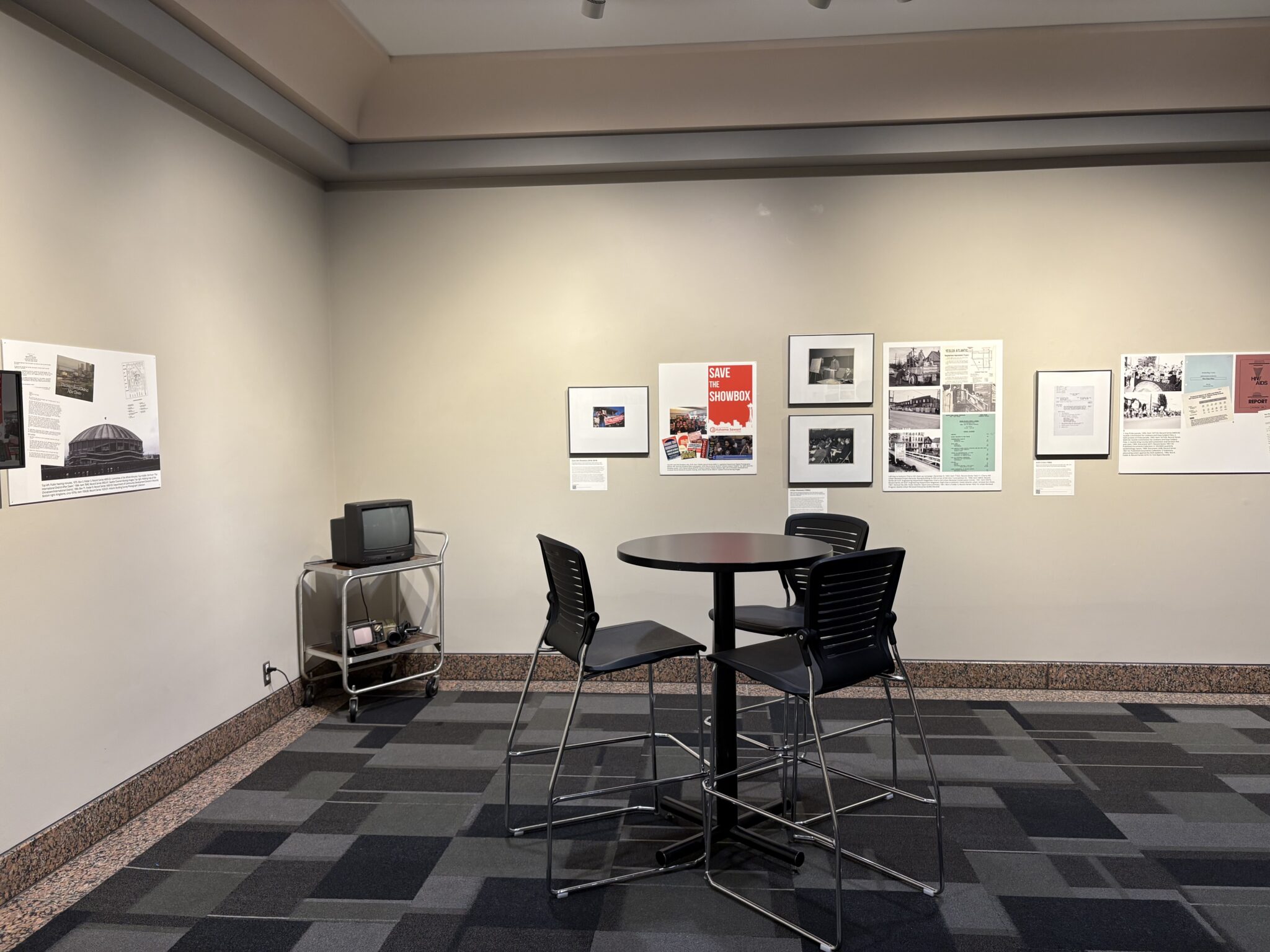 Image of gallery with items on walls and TV on cart in corner