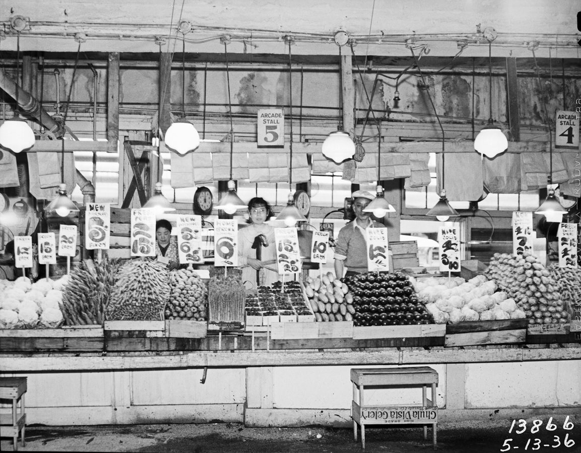 Black and white photo of Japanese farmers at produce booth in Pike Place Market