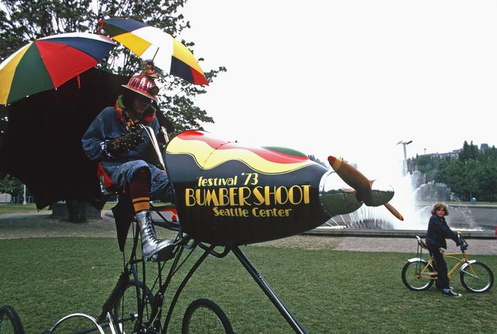 person riding fanciful rocket bicycle painted with "Festival '73 - Bumbershoot - Seattle Center"